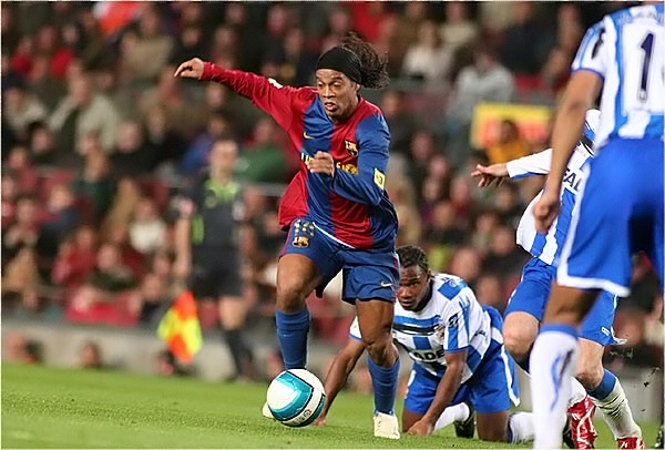 Ronaldinho #10 du FC Barcelone dribble et laisse deux défenseurs à terre au Camp Nou